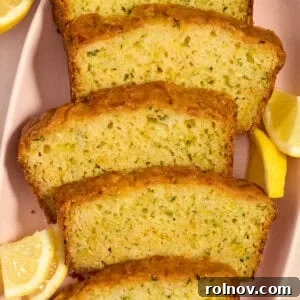 Moist Lemon Zucchini Bread with Citrus Glaze 14 Slices of lemon glazed lemon zucchini bread on plate with lemon wedges.