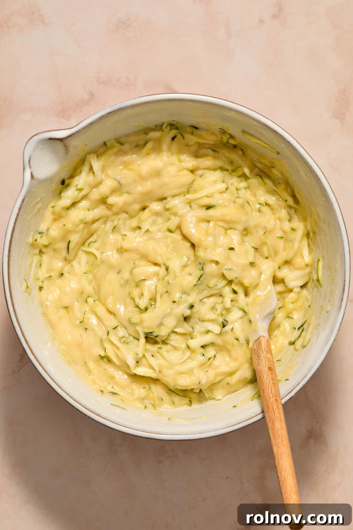 Moist Lemon Zucchini Bread with Citrus Glaze 9 Zucchini folded into batter in bowl with spatula.