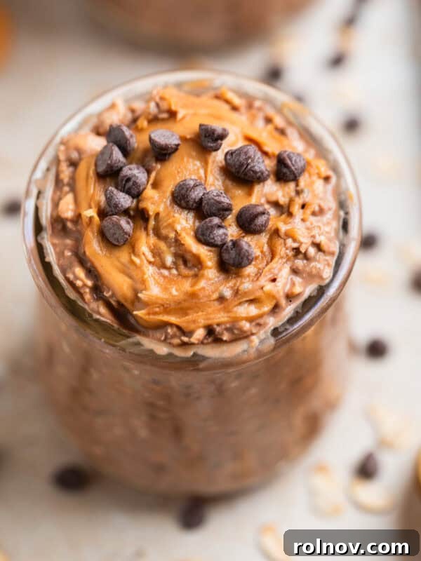 Chocolate chip and peanut butter topped chocolate overnight oats in glass.