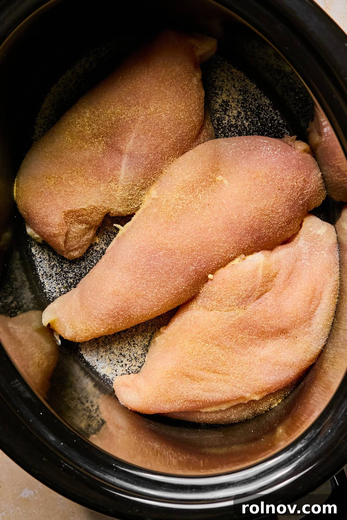 Sticky Honey Sriracha Slow Cooker Chicken 5 Seasoned chicken breasts in crockpot before cooking.