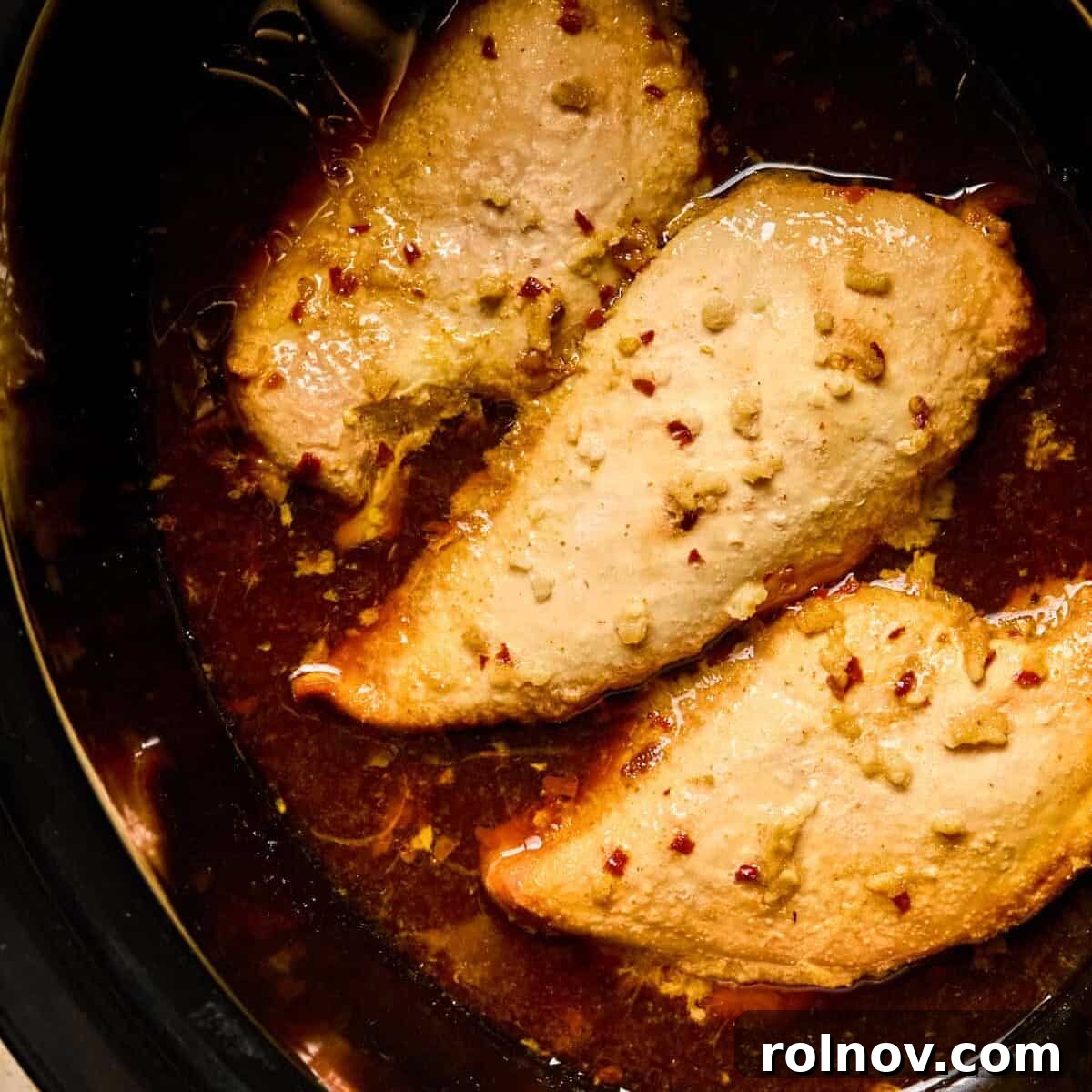 Sticky Honey Sriracha Slow Cooker Chicken 8 Cooked honey garlic sriracha chicken breasts in crockpot.