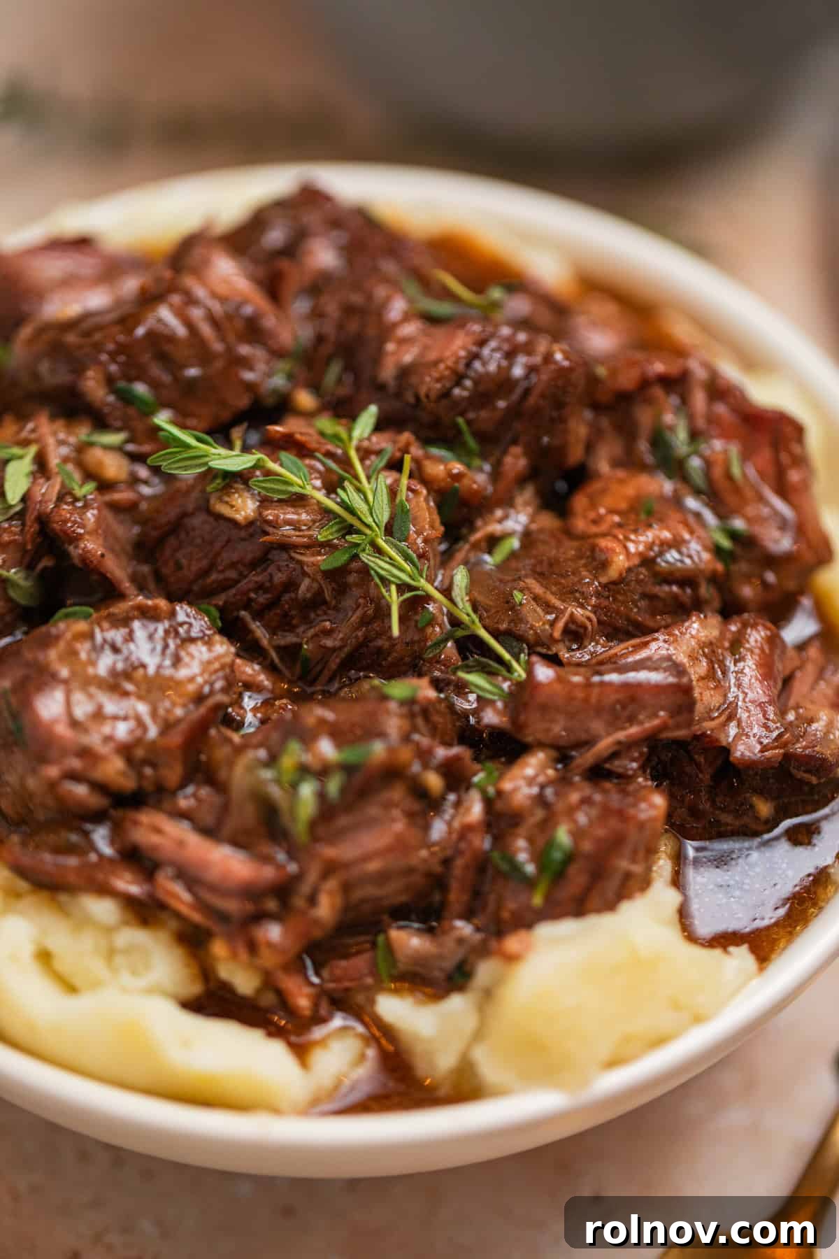 Mashed potatoes with chuck roast beef cubes and gravy topped with fresh thyme.