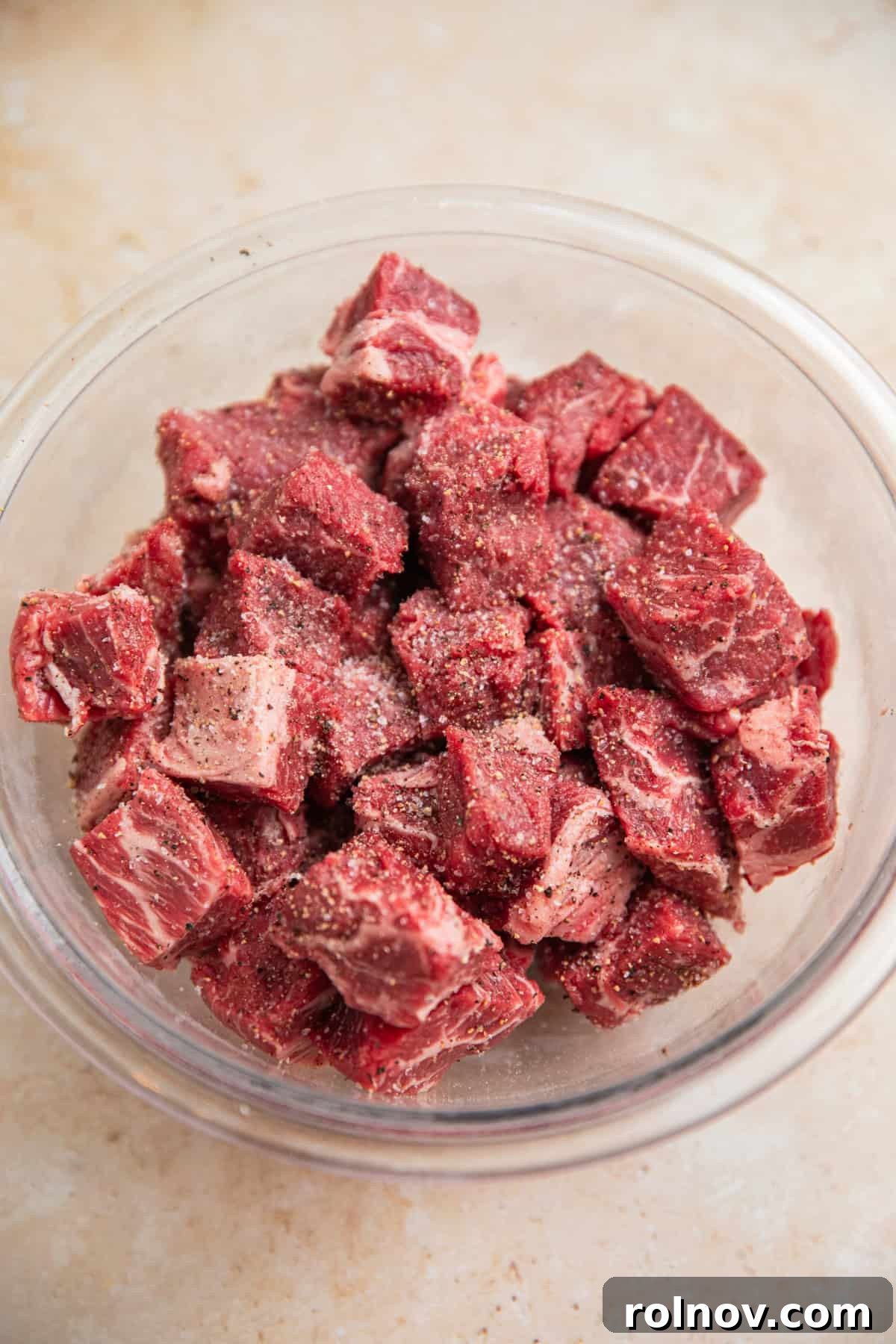 Cubed chuck roast in bowl with salt and pepper.
