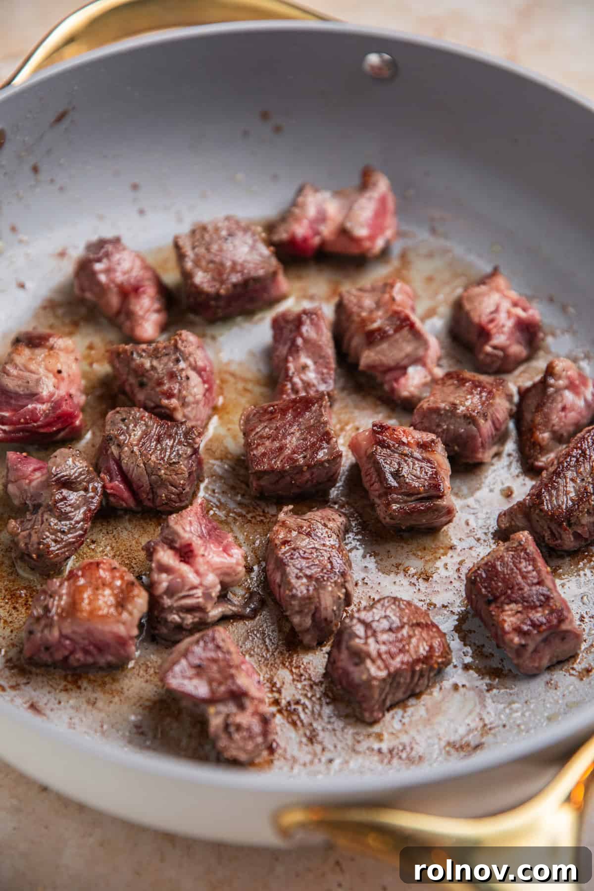 Seared beef cubes in skillet.