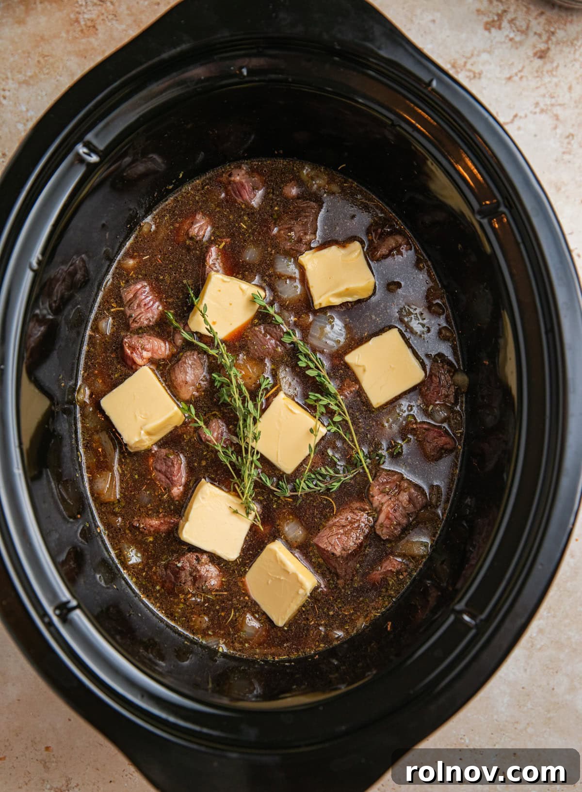 Butter and sprigs of thyme over top of beef tips in crock pot.
