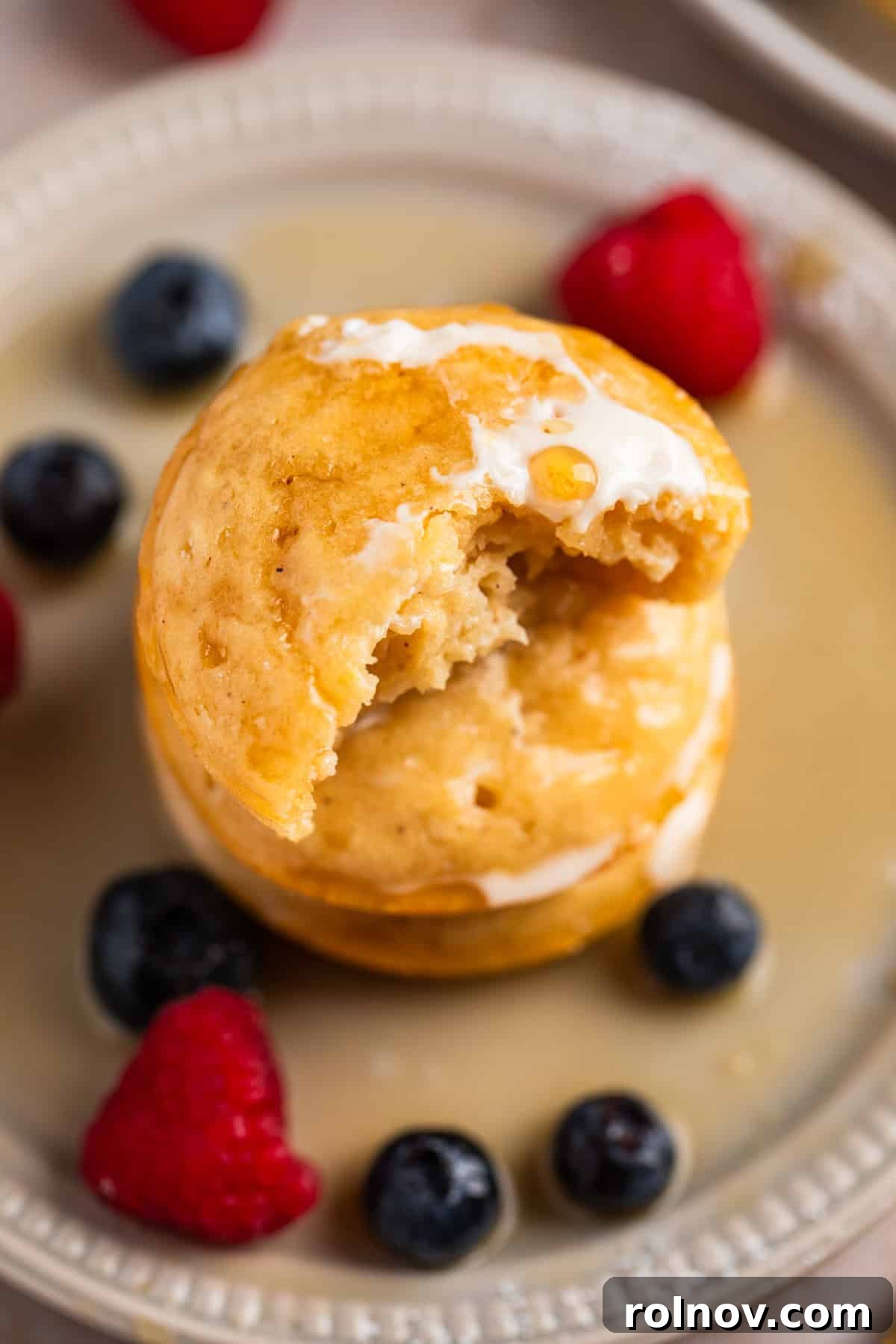 Stack of pancake bites on plate with butter and maple syrup.