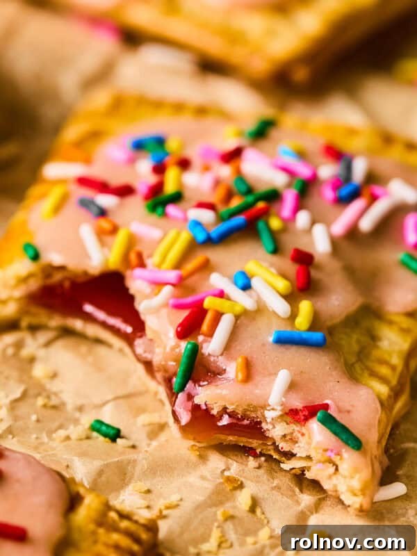 Homemade pop tart with pie crust on parchment with bite taken out.