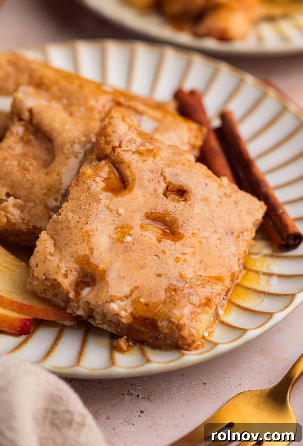 Sheet-Pan Apple Pancakes with Cinnamon 2 Apple cinnamon protein sheet pan pancakes on plate with syrup and cinnamon sticks.