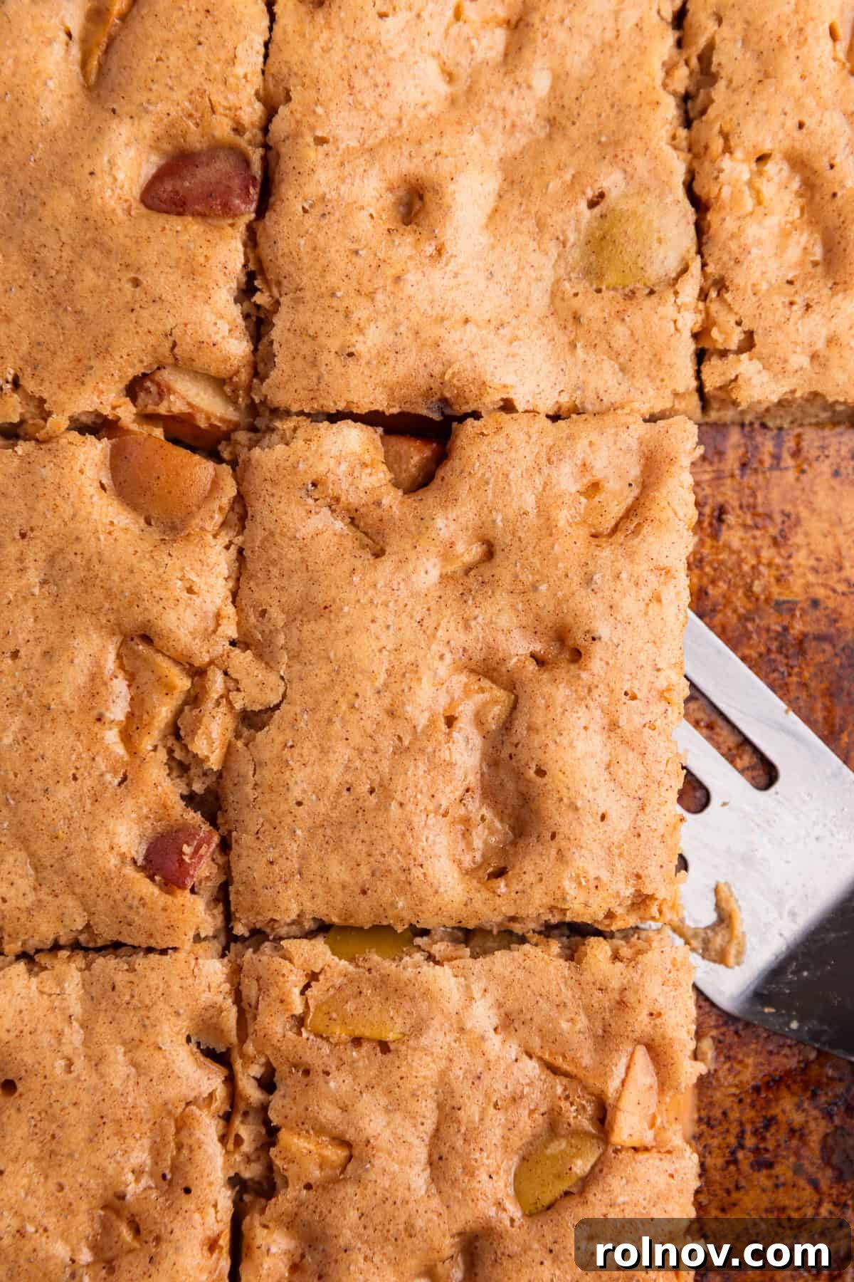Sheet-Pan Apple Pancakes with Cinnamon 10 Sliced sheet pan apple cinnamon protein pancakes with spatula.