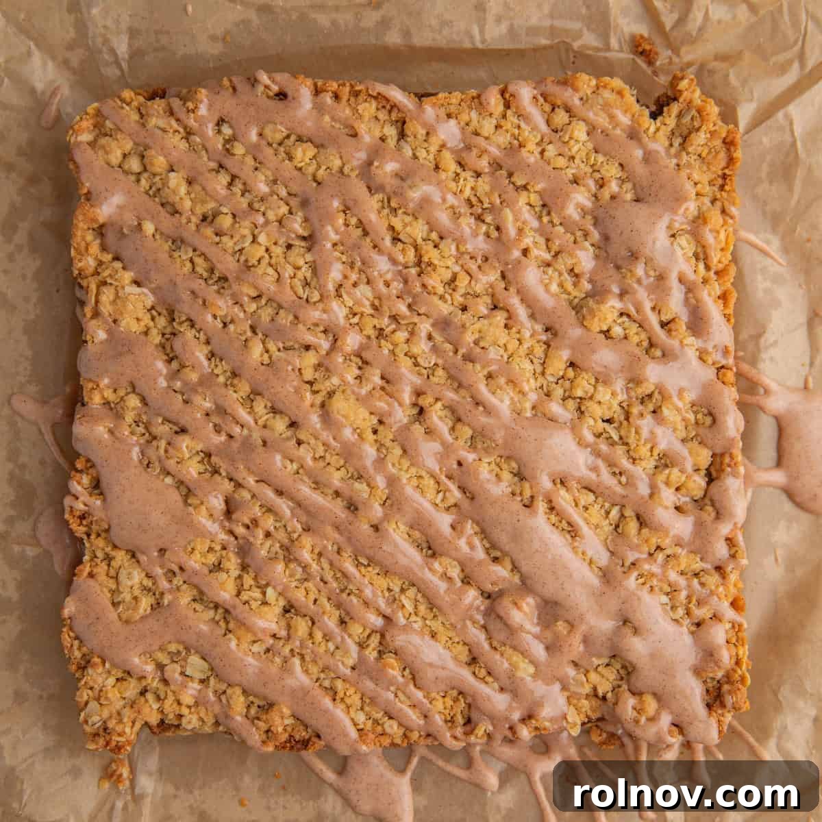 Cinnamon drizzle over oatmeal crumb bars on parchment.
