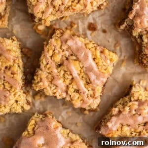 Brown sugar cinnamon oatmeal bars with cinnamon icing drizzle on parchment.