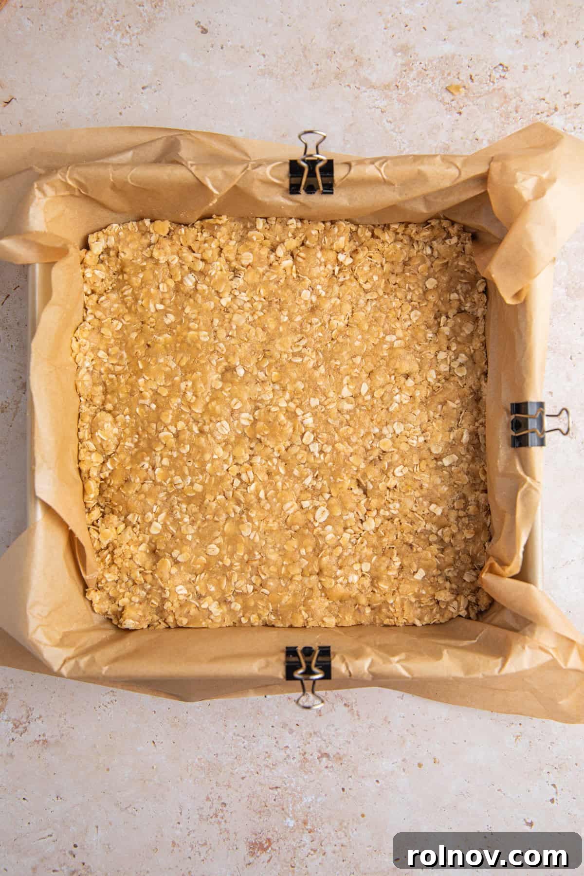 Oat crumb base layer pressed into baking pan lined with parchment.