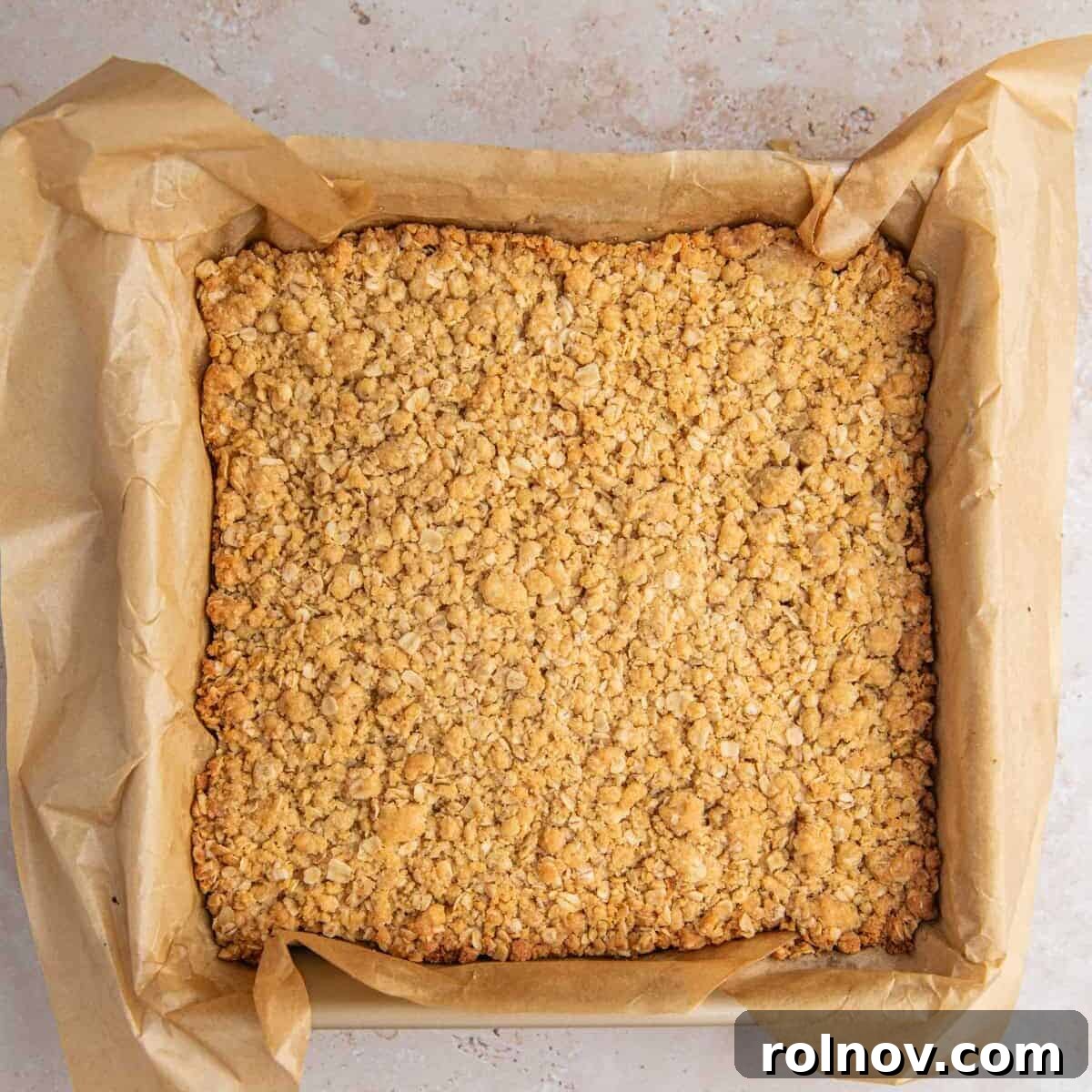 Baked oatmeal cinnamon crumb bars in parchment lined pan.