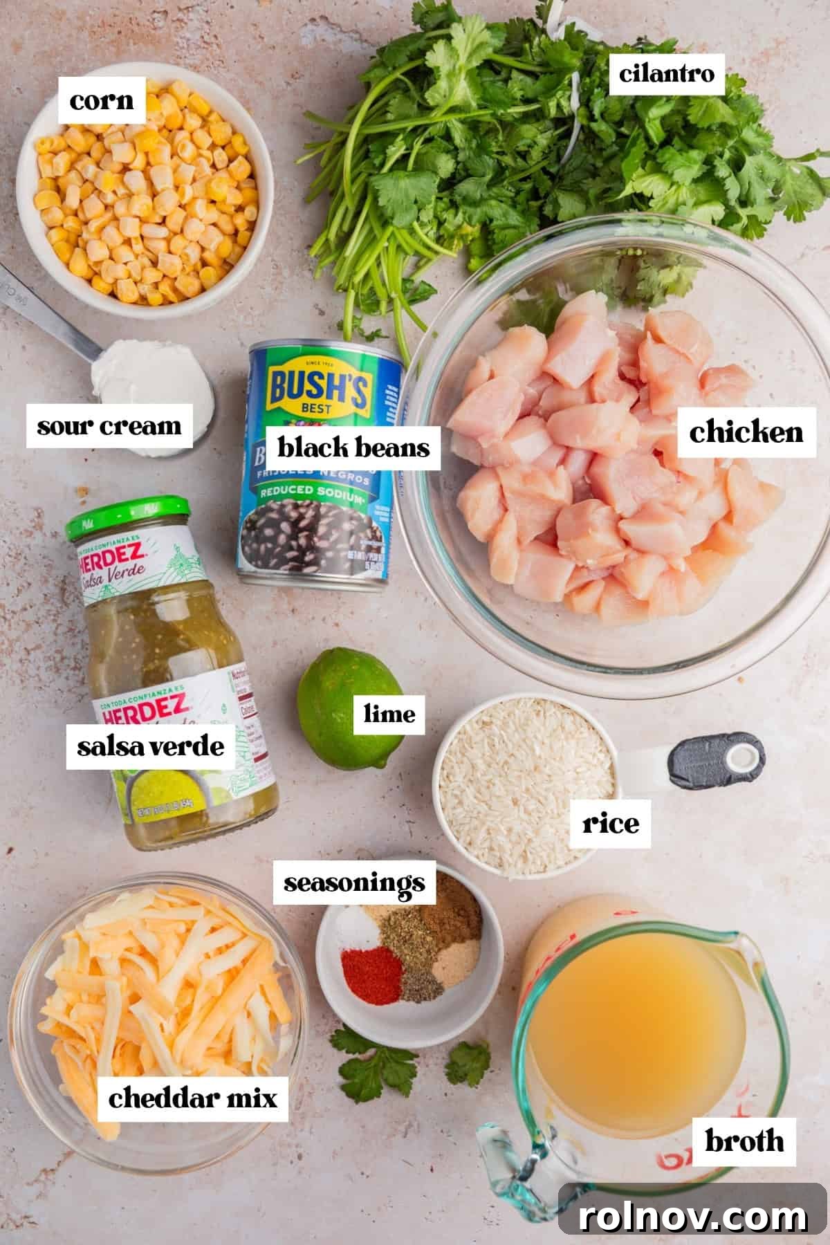 Cubed chicken, cilantro, corn, beans and other ingredients labeled on surface.