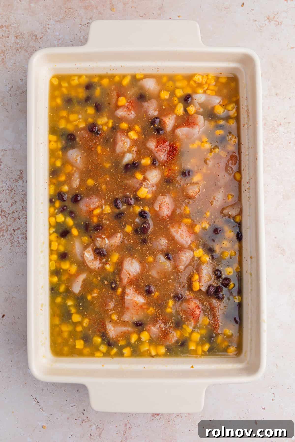 Salsa verde, broth, chicken, corn, beans and seasoning in pan.