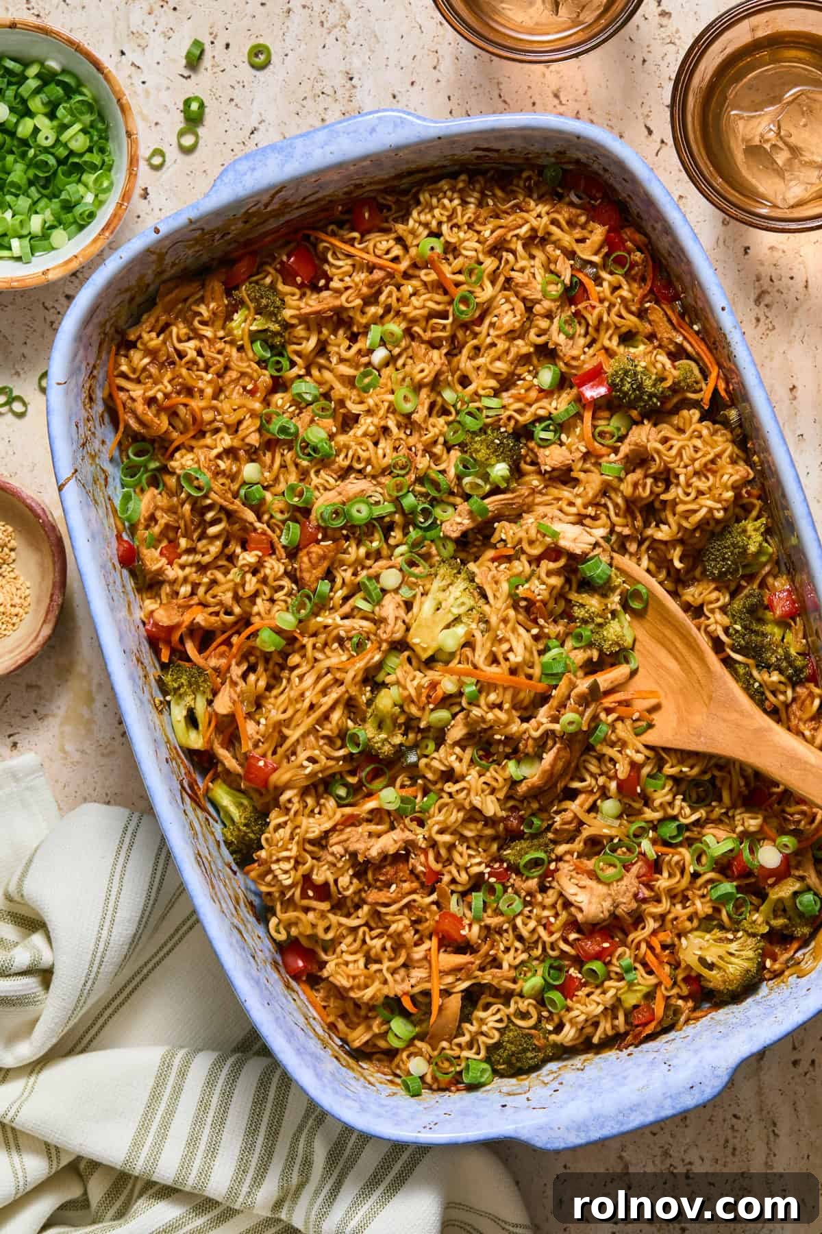 Blue pan with chicken and ramen bake and wooden spoon scooping in.