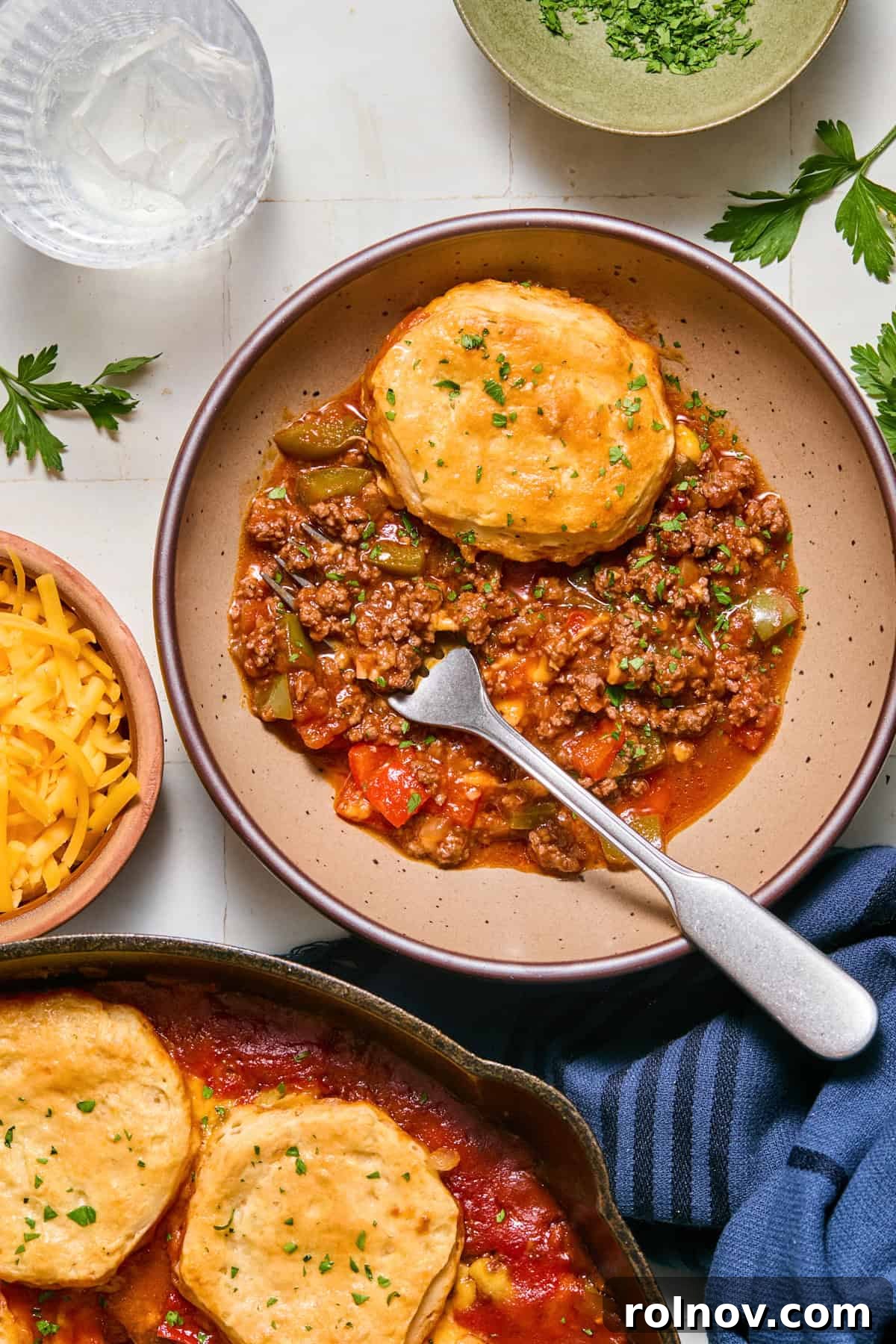 Cheesy Sloppy Joe Casserole for Family Weeknight Dinners 13 Dish with biscuit topped sloppy Joe mixture with fork.