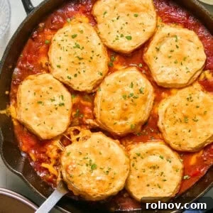 Cheesy Sloppy Joe Casserole for Family Weeknight Dinners 18 Cheese and biscuit topped sloppy Joe mixture in pan with serving spoon.