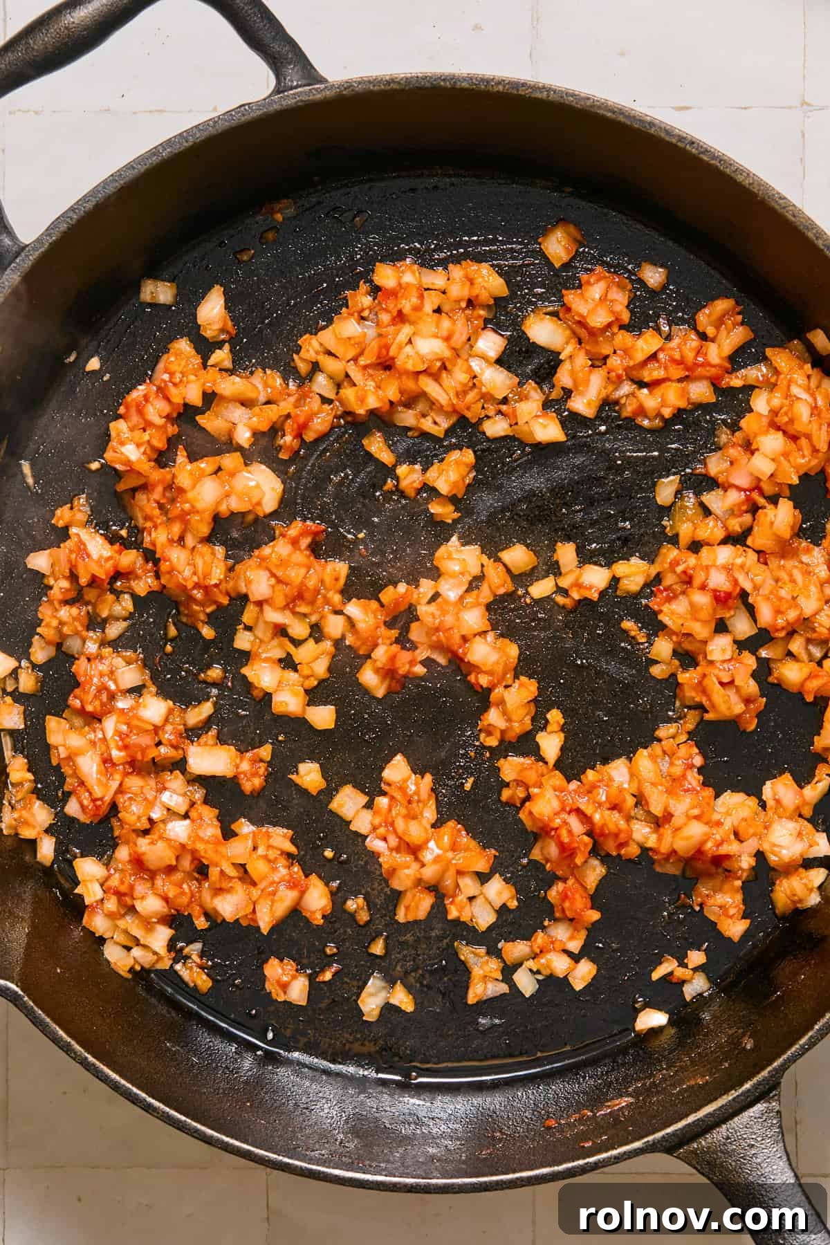 Cheesy Sloppy Joe Casserole for Family Weeknight Dinners 6 Onions, garlic and tomato paste in cast iron skillet.