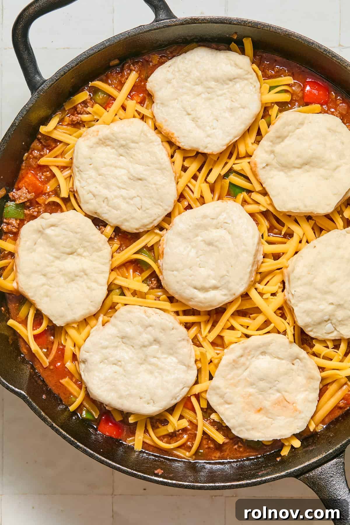 Cheesy Sloppy Joe Casserole for Family Weeknight Dinners 10 Biscuits and cheese over skillet with sloppy joe mixture.