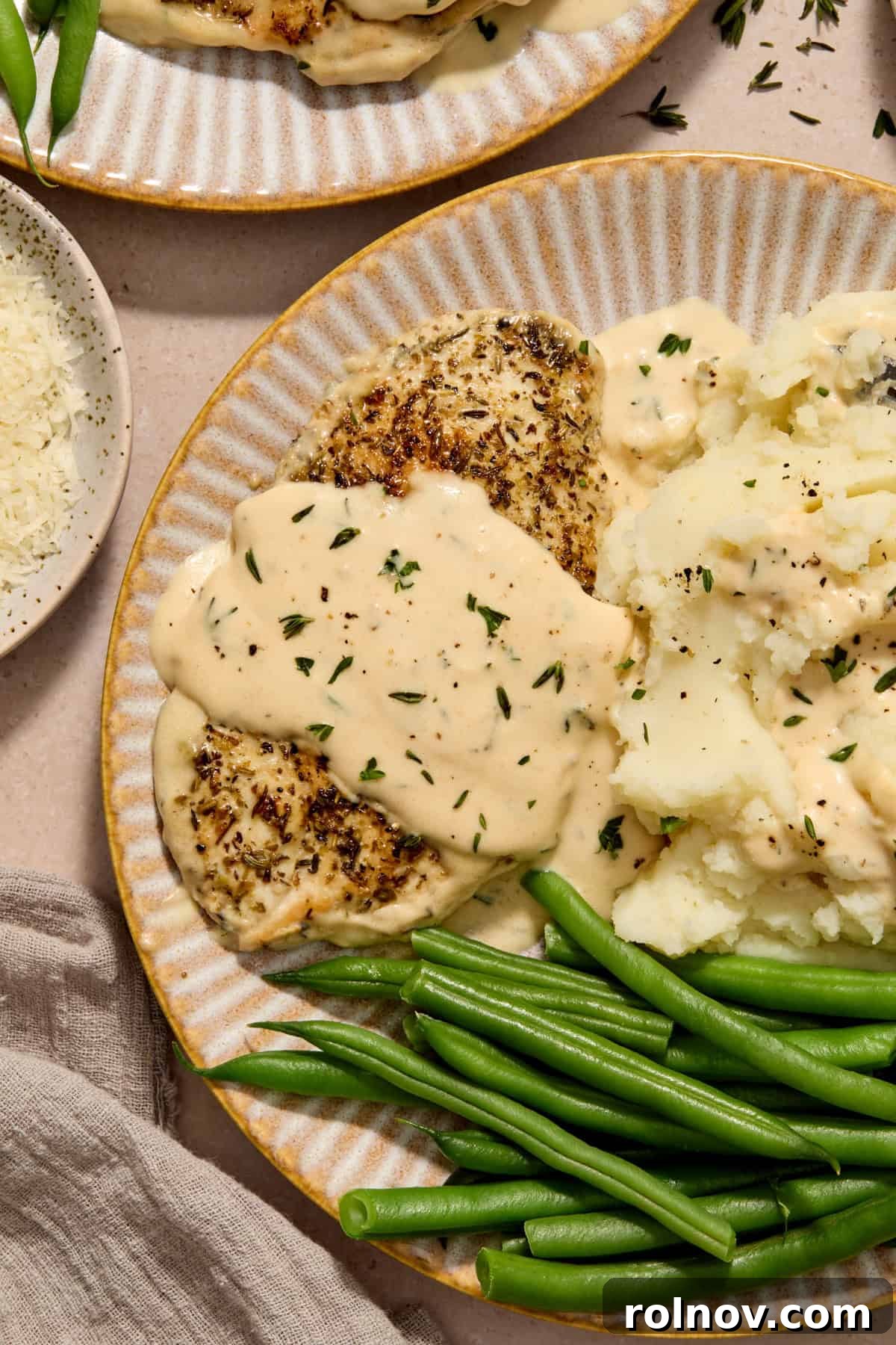 Creamy Garlic Parmesan Chicken Recipe 11 Chicken cutlet with creamy garlic parmesan over top on plate with mashed potatoes and green beans.