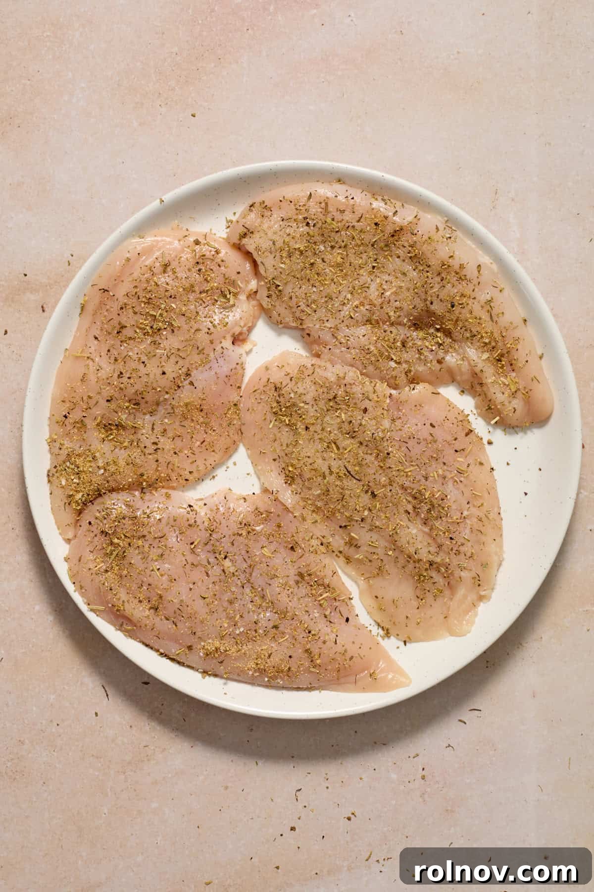 Creamy Garlic Parmesan Chicken Recipe 5 Seasoned chicken breast on plate before cooking.