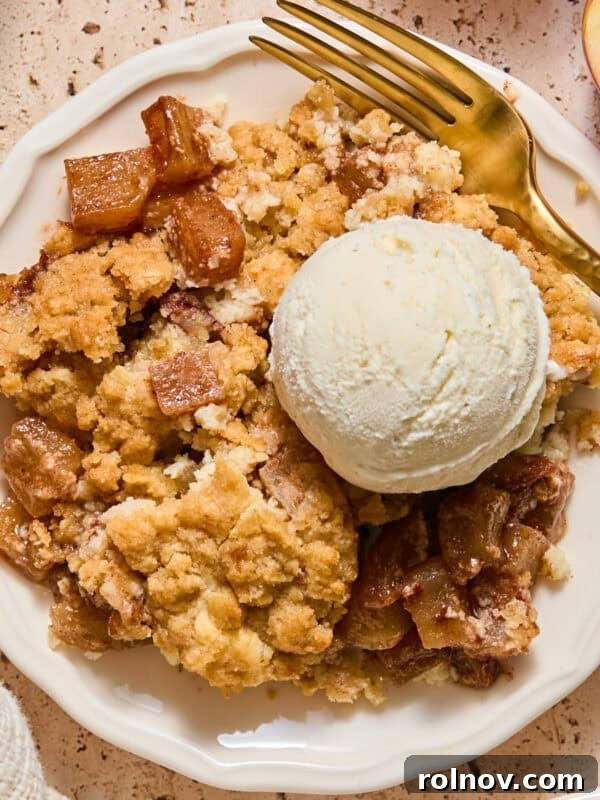 Apple cream cheese cobbler on plate with scoop of vanilla ice cream.