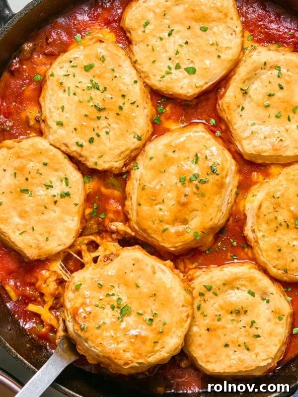 Cheese and biscuit topped sloppy Joe mixture in pan with serving spoon.