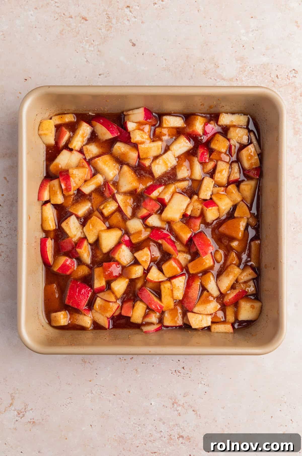 Warm Apple Cinnamon Biscuit Casserole 5 Diced apples added to baking pan with brown sugar and cinnamon mixture.