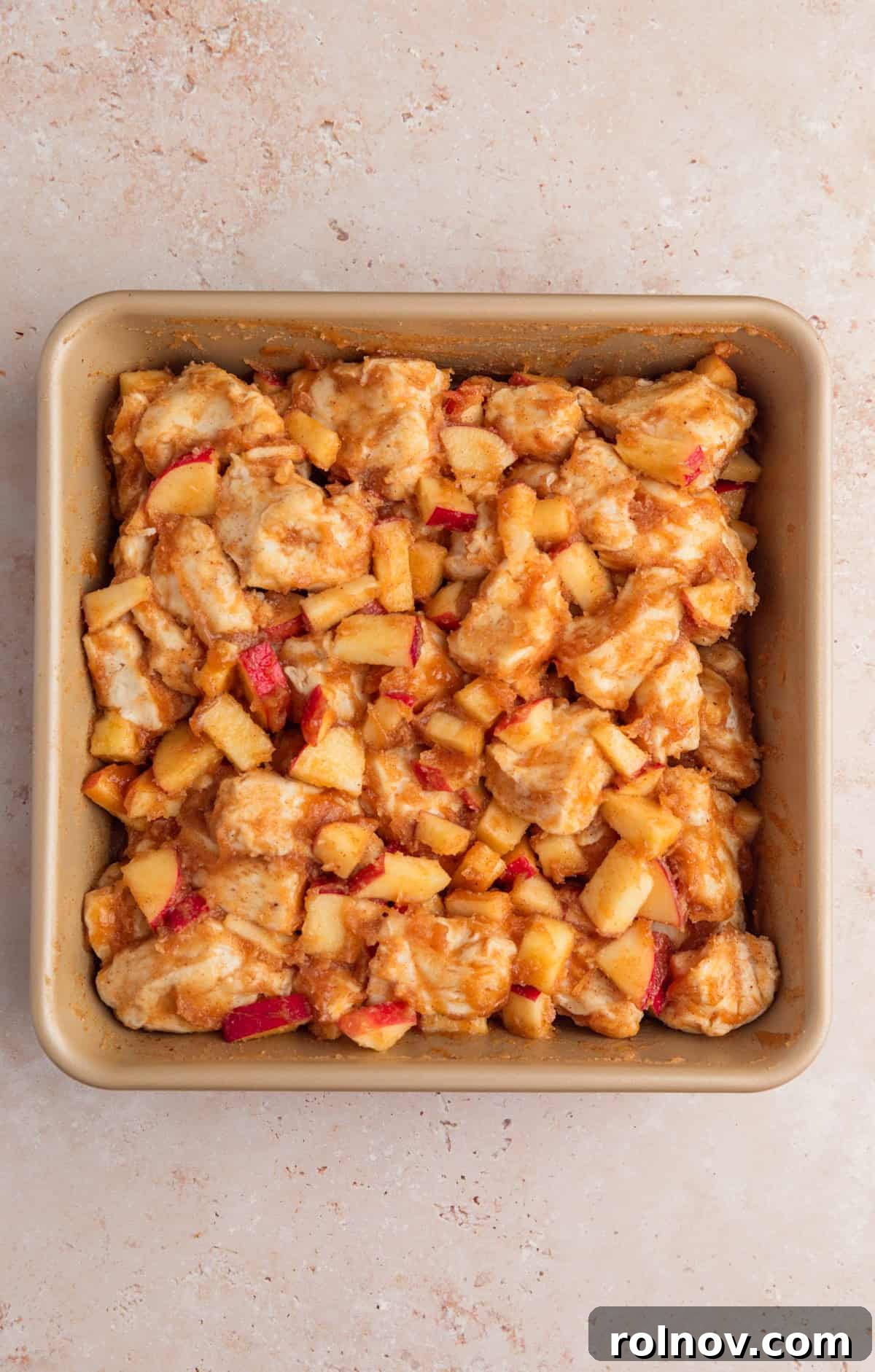 Warm Apple Cinnamon Biscuit Casserole 6 Biscuit dough pieces in baking dish with apples and cinnamon.