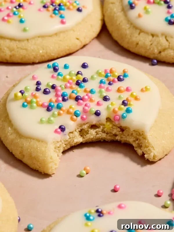 Eggless sugar cookies on surface with bite taken out of cookie.