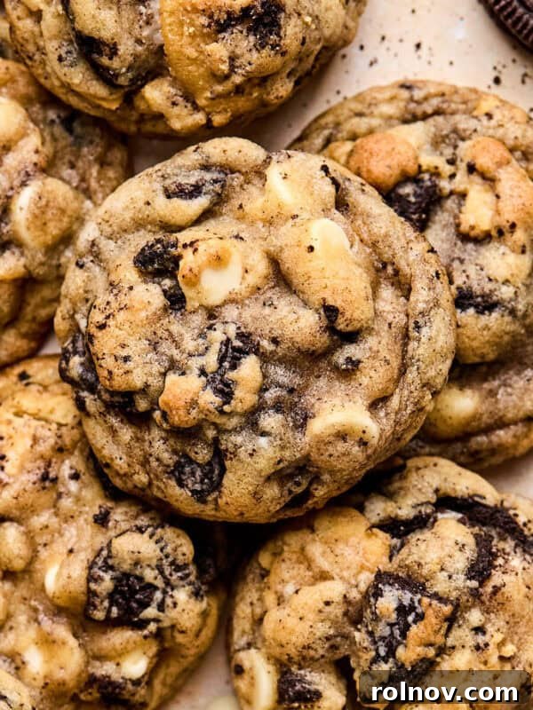 Oreo chocolate chip cookies arranged on surface with white chocolate chips and crumbs around them.
