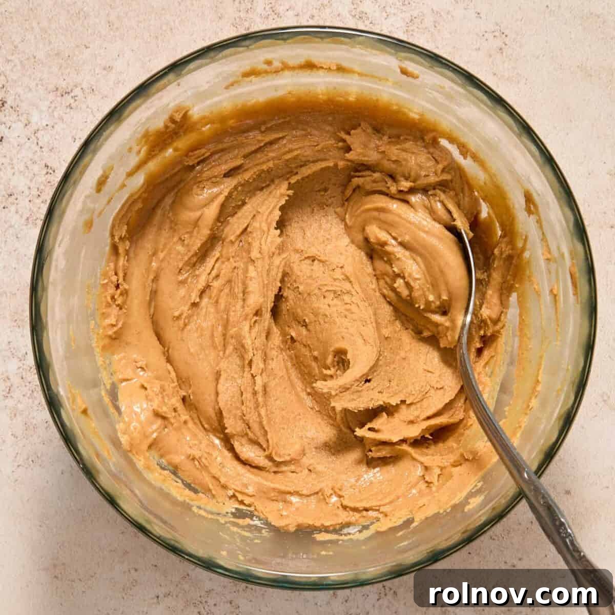 Peanut butter and powdered sugar mixed in bowl with spoon.
