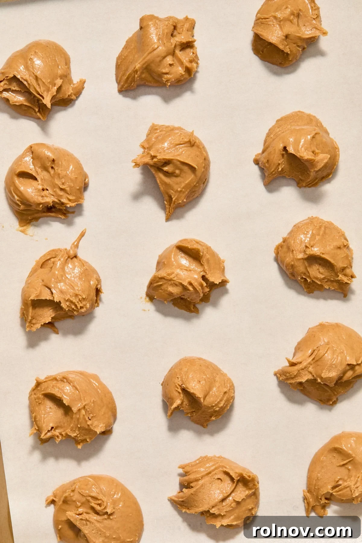 Peanut butter dollops on parchment lined pan.