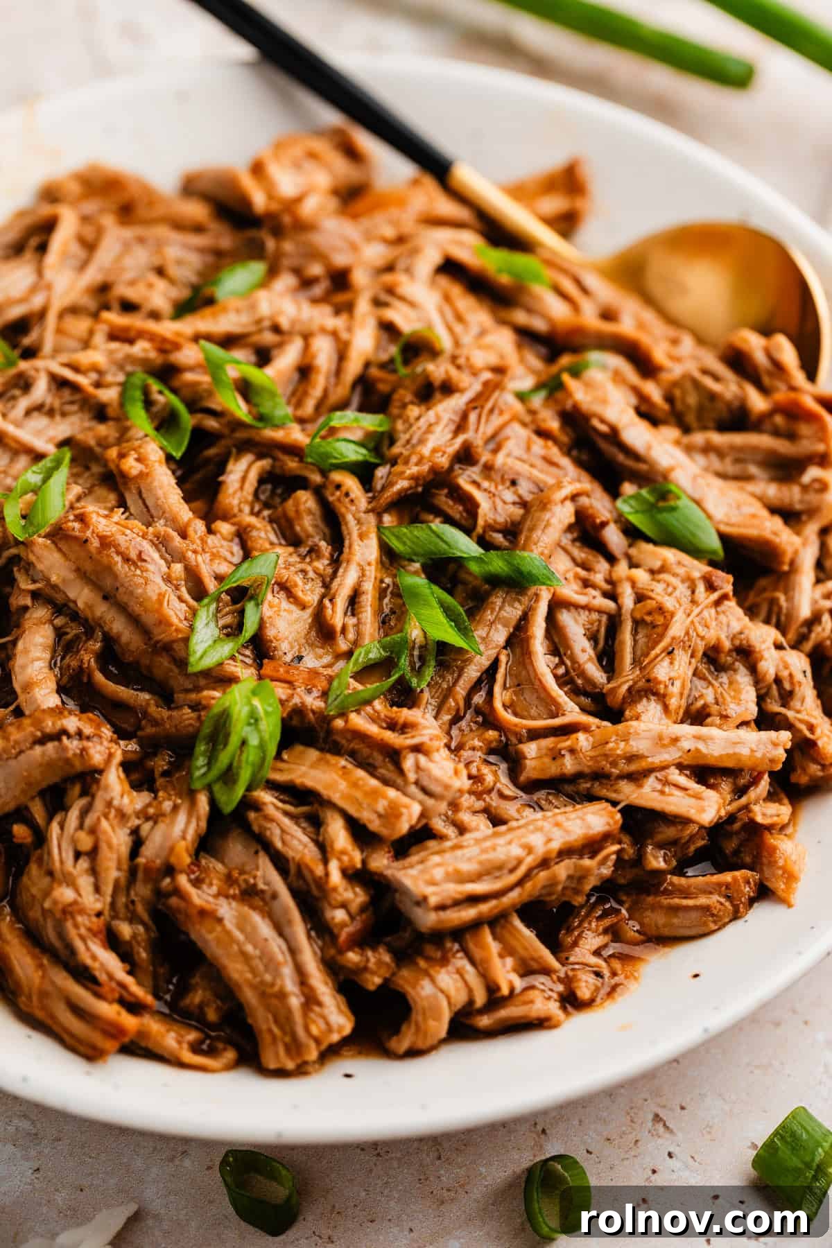 Honey Garlic Pork Tenderloin in the Slow Cooker 2 Slow cooker honey garlic pork tenderloin on plate topped with sliced green onions.